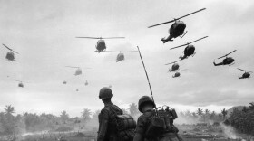 The second wave of combat helicopters of the 1st Air Cavalry Division fly over an RTO and his commander on an isolated landing zone during Operation Pershing, a search and destroy mission on the Bong Son Plain and An Lao Valley of South Vietnam, during the Vietnam War. The two American soldiers are waiting for the second wave to come in.