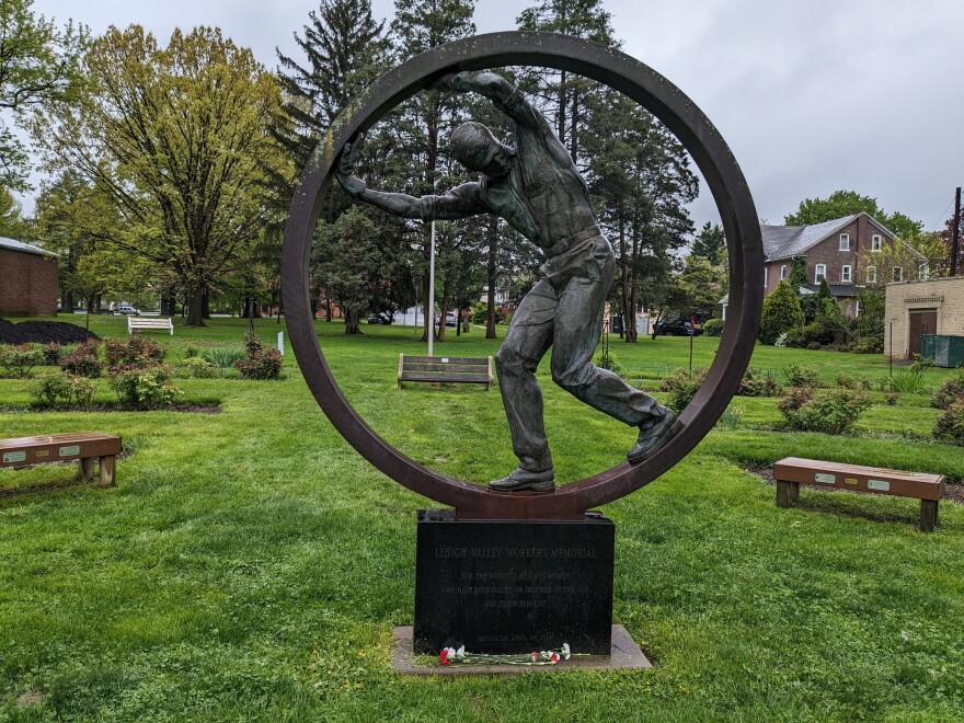 A bronze statue of a worker inside a large steel ring