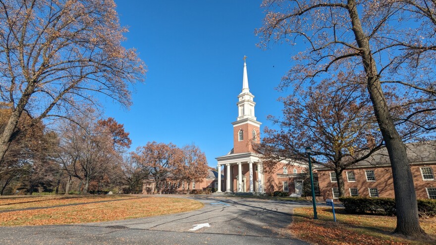 a very large church surrounded by lots of land, a few trees and a very blue sky