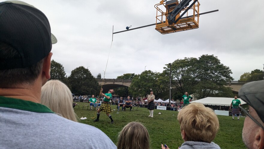 a man hurls a metal ball over a metal bar held about 17 feet over his head