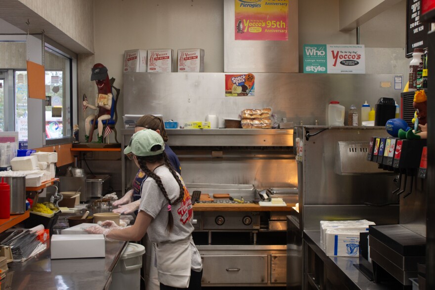 Behind the counter at Yocco's. In the top left corner, there is another, smaller Yocco's hotdog statue, made of porcelain.