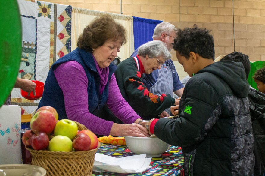 Volunteers teach kids how to make applesauce