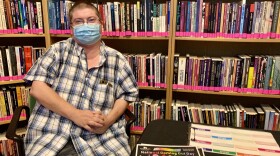 Bradbury-Sullivan's Youth Programs Manager Kim Ketterer sits at a table with a flier that says "National Coming Out Day." The flier has outlines of people in rainbow colors.