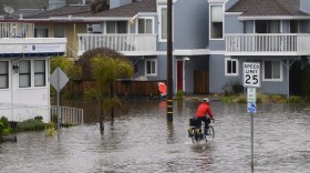 A man rides his bicycle on a flooded roadway in Aptos, California on Monday. More storms are expected Tuesday and Wednesday.