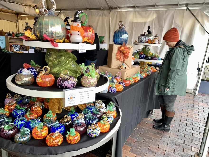A three-tiered table is filled with glass pumpkins of various colors and sizes.