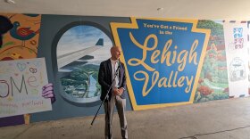 Bethlehem mayor J William Reynolds stands in front of a colorful mural with the words "you've got a friend in the lehigh valley"