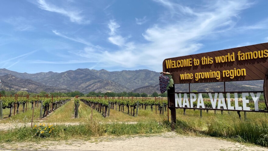 Wildfire-scarred hills are visible behind the famous sign welcoming visitors to Napa Valley.