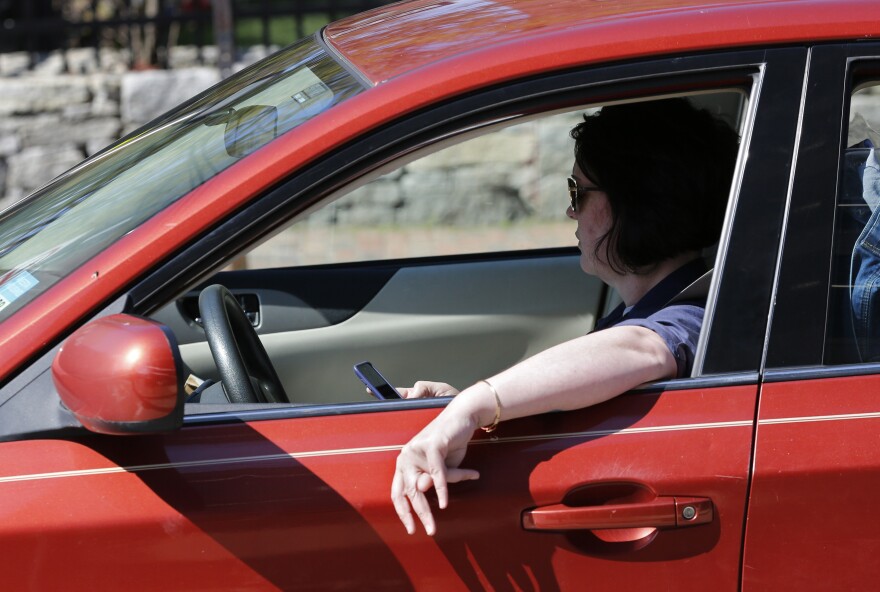 In this file photo, a driver uses his cell phone while driving in Portland, Maine. A bill to ban the use of handheld cellular devices while driving in the state took effect in 2019. Similar legislation has been introduced in Pennsylvania in 2023.