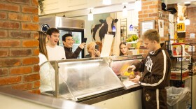 a man in a brown Lehigh University jumpsuit scoops some ice cream.