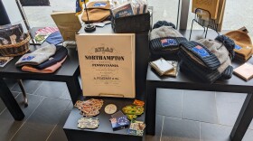A store display centered around a reproduction of an 1876 atlas of Northampton County. there are a lot of winter hats and stickers.