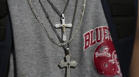 A student wears a pair of cross necklaces.