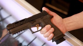 A Sig Sauer P320 handgun is held at a store.