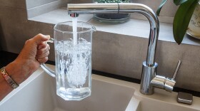 A pitcher is filled with tap water at a sink