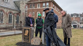 Five people in winter cloths gather around a stone monument to Martin Luther King and his wife Coretta Scott King. It looks like two rounded headstones with a small plaque in the middle