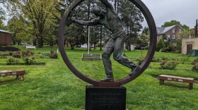 A bronze statue of a worker inside a large steel ring
