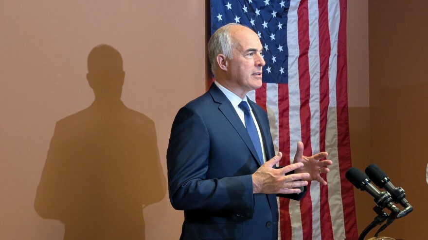 Bob Casey stands at a podium in front of a flag.