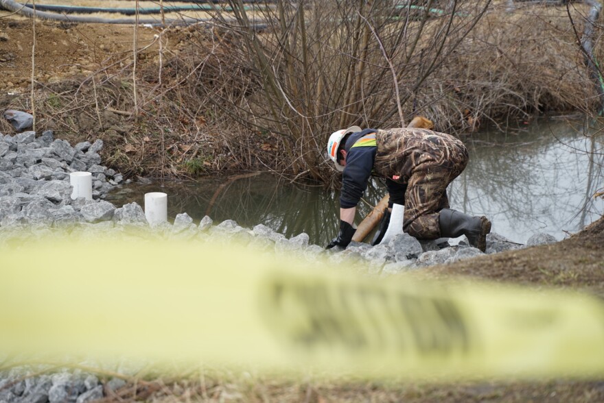  An environmental remediation worker attends to the Leslie Run stream in the East Palestine City Park. Dead fish have been found in the stream.