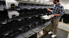 An election official gathers mail-in ballots being sorted in Chester County, Pa. Officials predict the  "overwhelming majority" of ballots will be tallied by Friday.