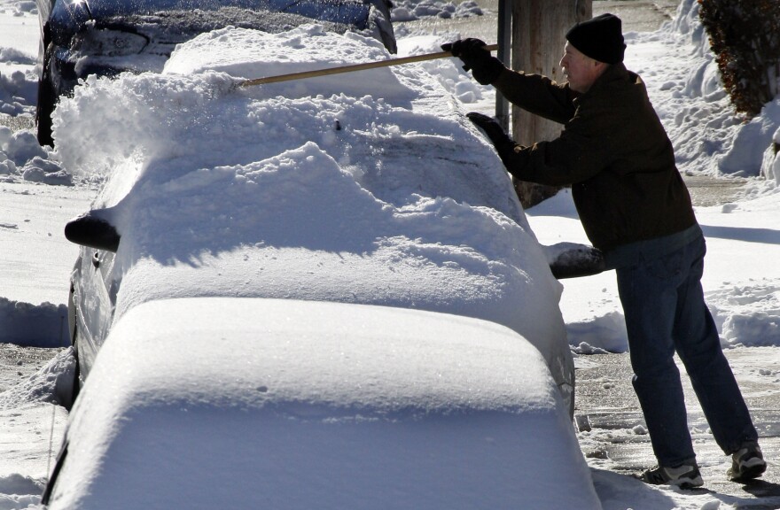 FILE - A resident of the Greenfield neighborhood of Pittsburgh brushes snow off a car, Tuesday morning,  Feb. 22, 2011, after more than 8 inches fell overnight in the area.