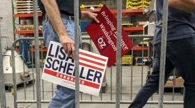 Participants walking into a warehouse holding signs for Oz and Scheller