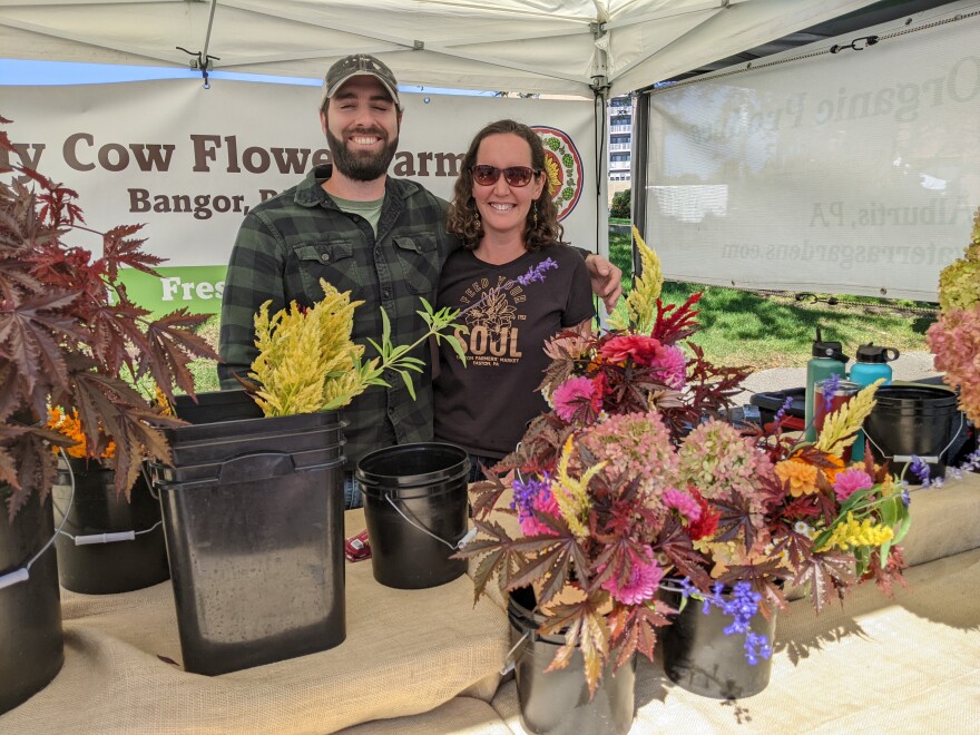 Holy Cow Flowers Farm has a table with a variety of flowers for sale at the market