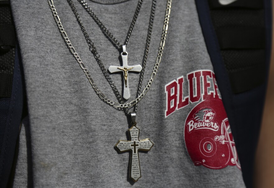 A student wears a pair of cross necklaces.