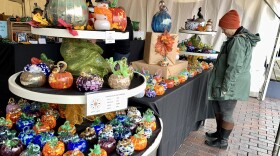 A three-tiered table is filled with glass pumpkins of various colors and sizes.