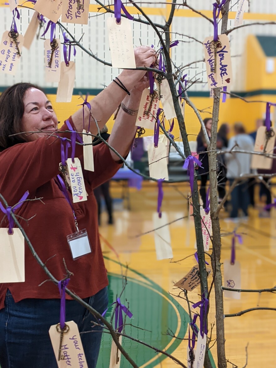 Vigil - Attendee hangs a key and message to tree full of messages of support.jpg